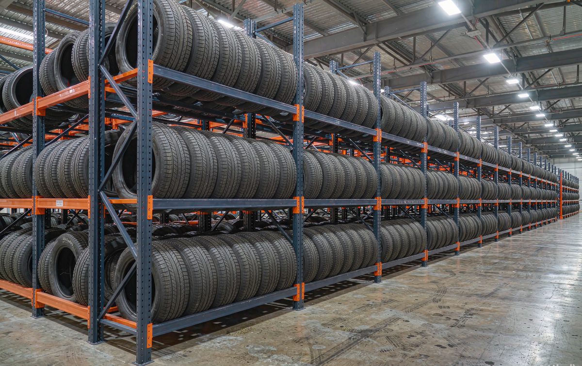 Tire shop warehouse with open steel tire racks storing rows of passenger tyres upright